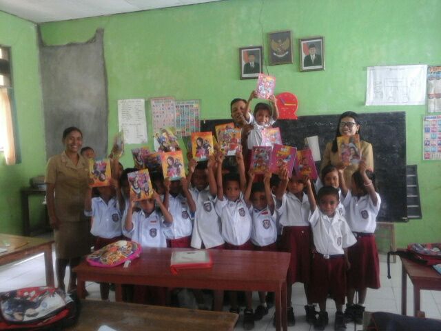 Anggota Bhabinkamtibmas Desa Kolobolon bagikan buku tulis kepada murid Sekolah Dasar